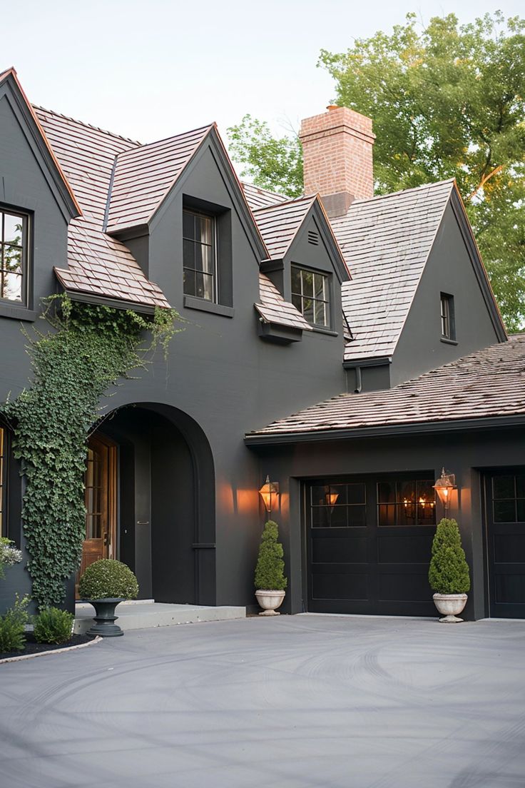 a large gray house with two garages and some plants on the side of it