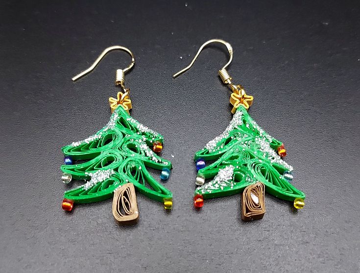 Are you looking for a special gift for someone or yourself? This is exactly what you are looking for. These beautiful hand crafted earrings are made from 1/8" thick quilling paper strips in green, brown and gold  colors. They are attached to hypo-allergenic silver plated earring hooks.  The earrings are coated with clear acrylic sealant to provide sturdiness to the jewelry. But it is not 100% water-proof. Please remove jewelry prior to swimming, bathing, or other water-based activities. In case of water contact, gently dab with a paper towel and allow to dry completely.  Please message me for custom order requests or questions. The rest of my collection is available at  https://breezechicdesigns.etsy.com Handmade Jewelry For Christmas Crafting, Handmade Jewelry For Christmas Celebration, Handmade Jewelry For New Year Holiday, Handmade Holiday Drop Earrings, Handmade Christmas Drop Earrings, Handmade Festive Earrings For Christmas, Holiday Handmade Earrings For Celebration, Green Festive Jewelry For New Year, Handmade Earrings For Holiday Celebrations