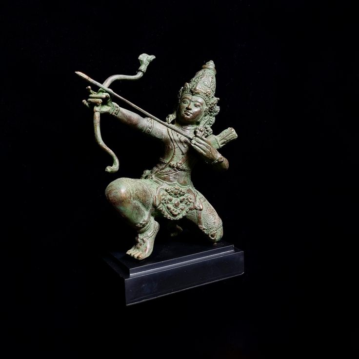 a bronze statue with a bow and arrow in it's hand on a black background