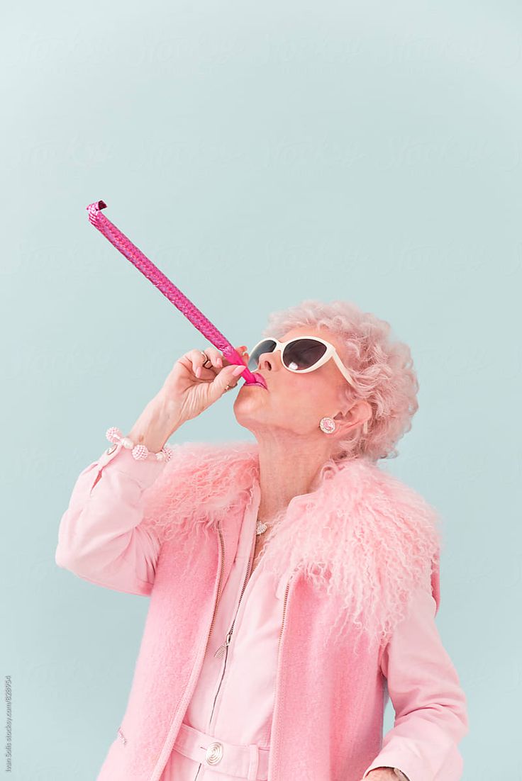 a woman in pink jacket and sunglasses holding a toothbrush