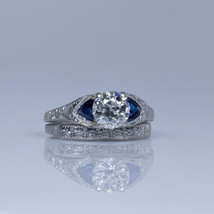 a diamond and blue sapphire ring on a reflective surface