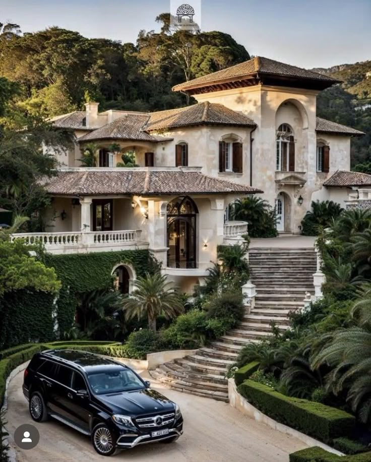 a black car is parked in front of a large house with steps leading up to it