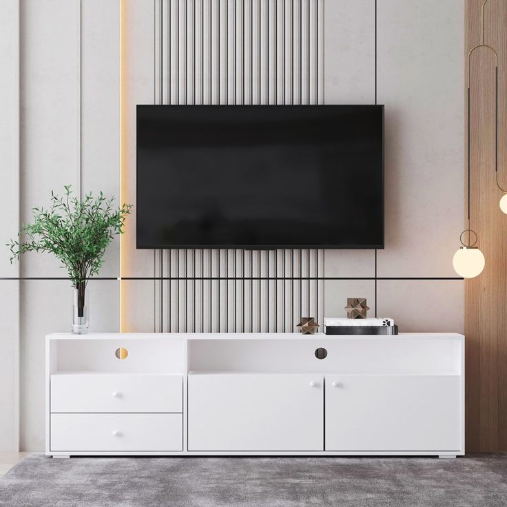 an entertainment center with a flat screen tv mounted on the wall and two white drawers