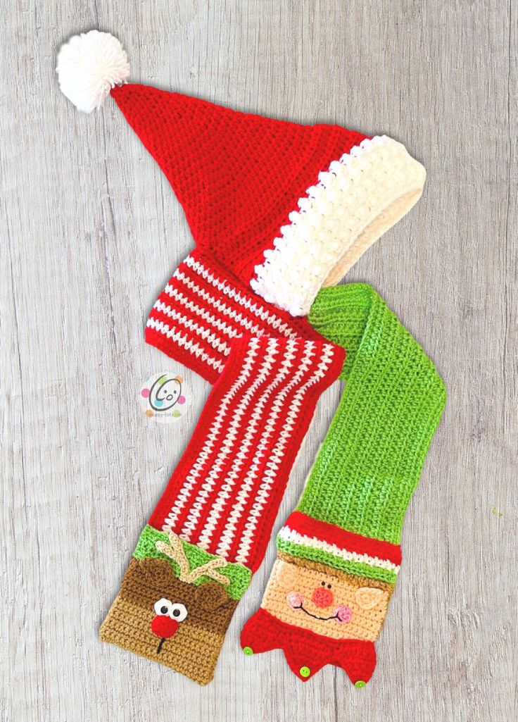 two knitted christmas hats and mittens laying on top of a wooden table next to each other