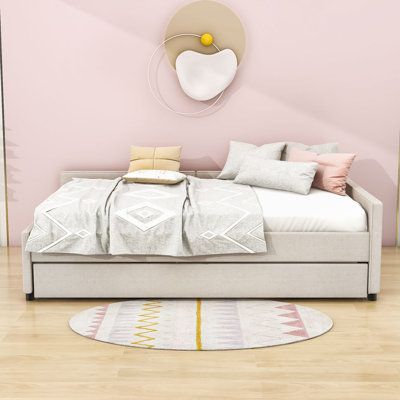 a bed sitting in the middle of a room next to a pink wall