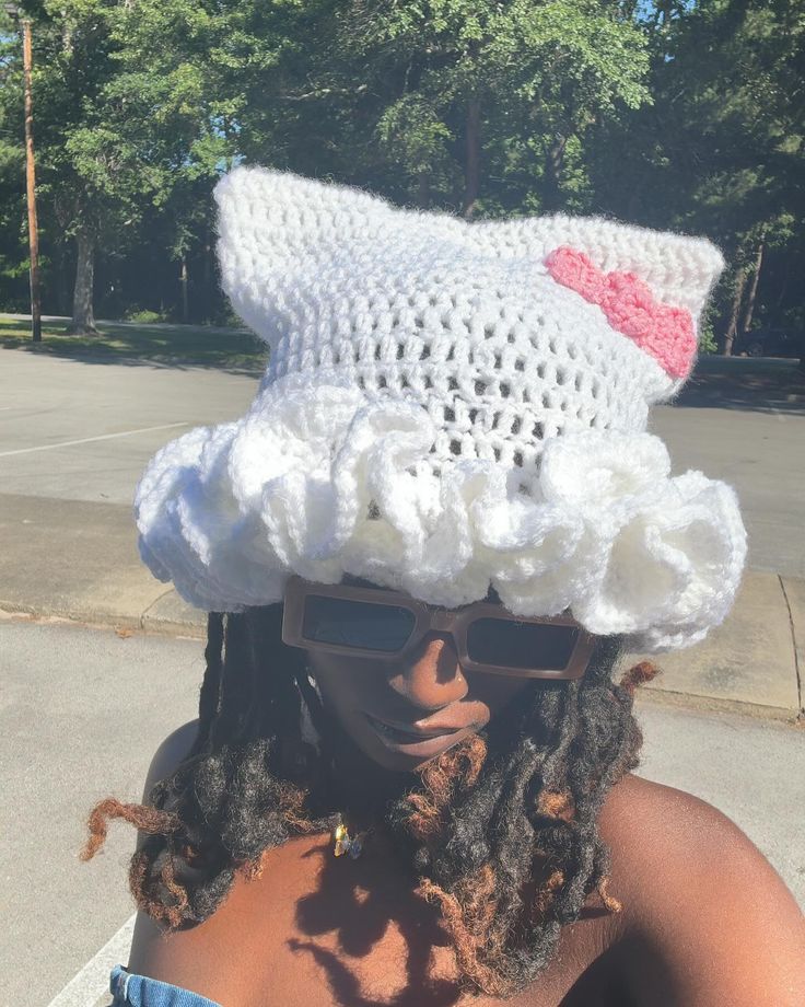 a woman wearing a crocheted hat and sunglasses