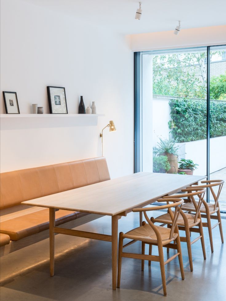 a wooden table and chairs in front of a window with an open wall behind it