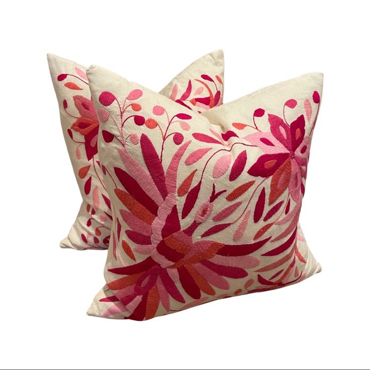 two pink and red decorative pillows sitting on top of each other