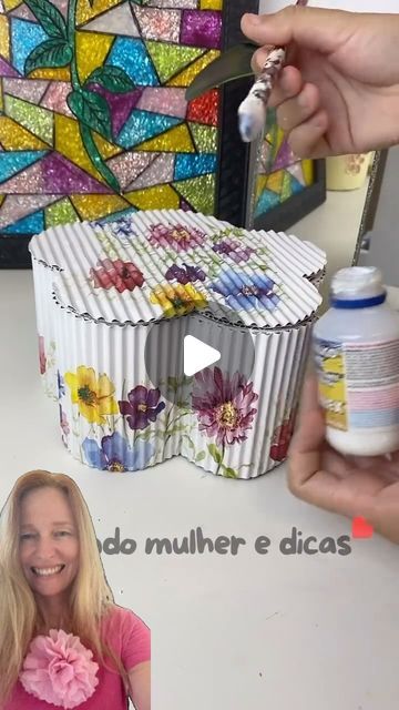 a woman sitting at a table in front of a cupcake tin with flowers on it