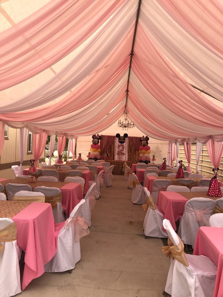 the inside of a pink and white tent with lots of tables set up for an event