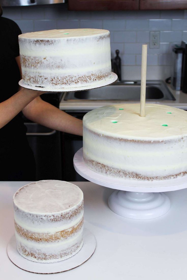 two cakes sitting on top of a white counter next to a woman in a black shirt