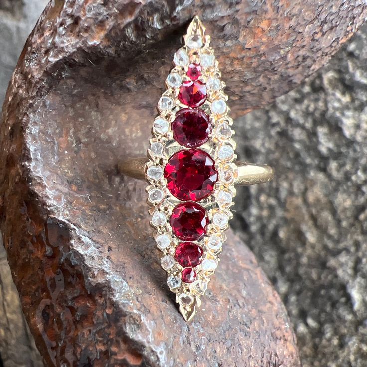 Gorgeous Synthetic Rubies accented by Diamonds set in a unique 10 Yellow Gold Navette Ring. US Size 6 1/2 Graduated Rubies approximately 1.36 tcw Diamonds approximately 0.36 tcw  Diamond Grading G/I2-I3 Widest Point measures approximately 30.1mm. Back of the shank tapers down to 1.9mm, approximately. Nicely weighted at 3.5 grams, approximately. Stamped 10k Ruby is the birthstone for July. Diamond is the birthstone for April. 14k Gold Red Multi-stone Cluster Ring, Heirloom 14k Gold Multi-stone Diamond Ring, Heirloom Multi-stone Diamond Ring In 14k Gold, Marquise Ruby Ring With Rose Cut Diamonds, Heirloom Multi-stone Marquise Cut Cluster Ring, Heirloom Red Jewelry With Diamond Accents, Antique Diamond Rings With Accent Stones, 14k Gold Marquise Diamond Ring With 17 Jewels, Heirloom Marquise Cut Multi-stone Cluster Ring