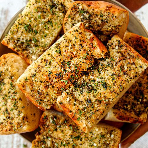 garlic bread cut into cubes on a plate with seasoning sprinkles