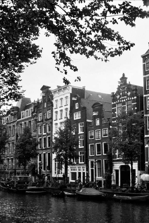 black and white photo of boats on the water in front of buildings with trees around them