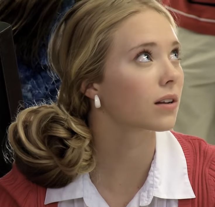 a woman in a red sweater and white shirt looking off into the distance with her eyes closed