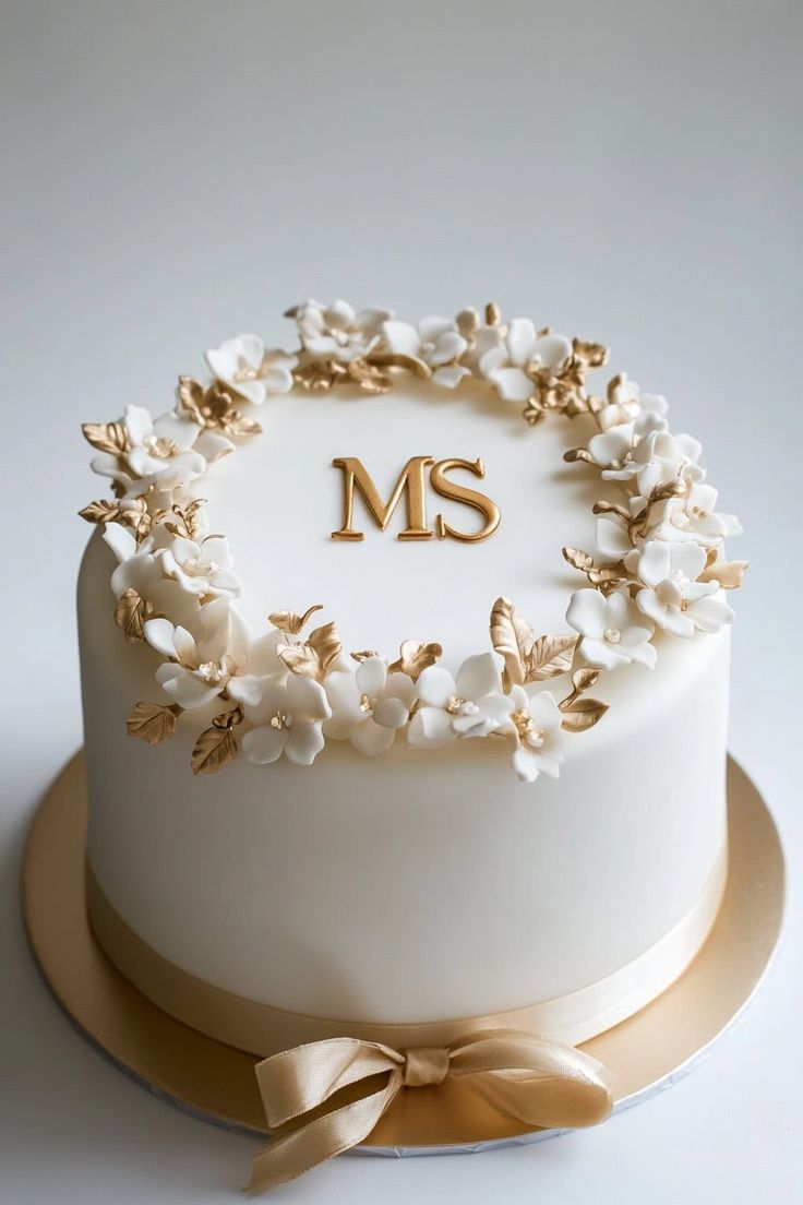 a white cake with gold decorations and the letter ms on it