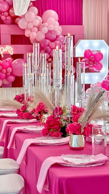 the table is set with pink flowers and candles for a birthday party or special occasion