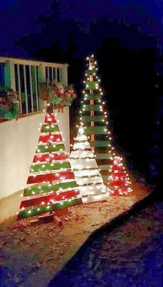 lighted christmas trees on the side of a house