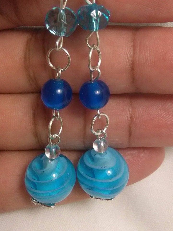 These earrings reminds me of the Caribbean Sea and wishing I was on a vacation. The earrings made with 10mm ocean blue glass beads, 2mm blue beads and 2 mm Czech beads. Perfect for any occasion. Blue Round Beaded Earrings, Blue Earrings With Colorful Round Beads, Blue Glass Wire Wrapped Earrings, Blue Wire Wrapped Glass Earrings, Blue Wire-wrapped Glass Earrings, Blue Czech Glass Beaded Earrings, Blue Round Beaded Earrings For Beach, Blue Czech Glass Beaded Earrings With Dangling Beads, Blue Beaded Earrings For Beach