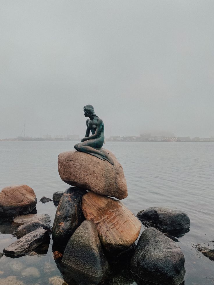 a statue sitting on top of rocks in the water