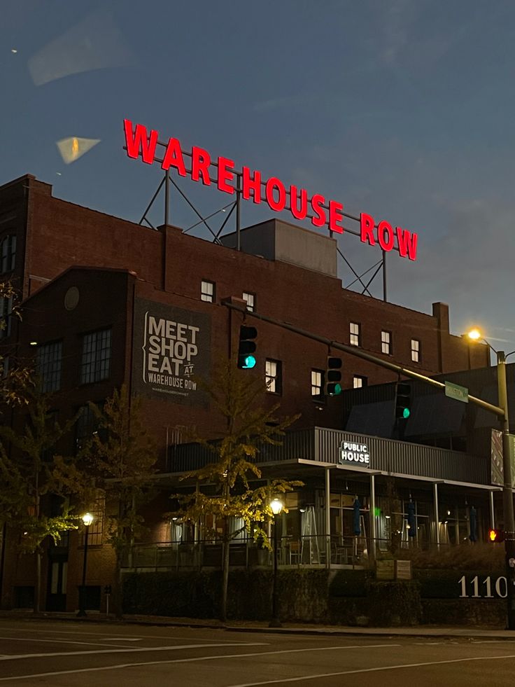 a red sign that reads warehouse row on top of a building in the city at night