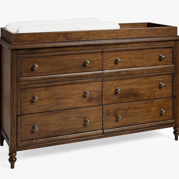 a wooden dresser with drawers and a white blanket on it's top shelf, against a white background