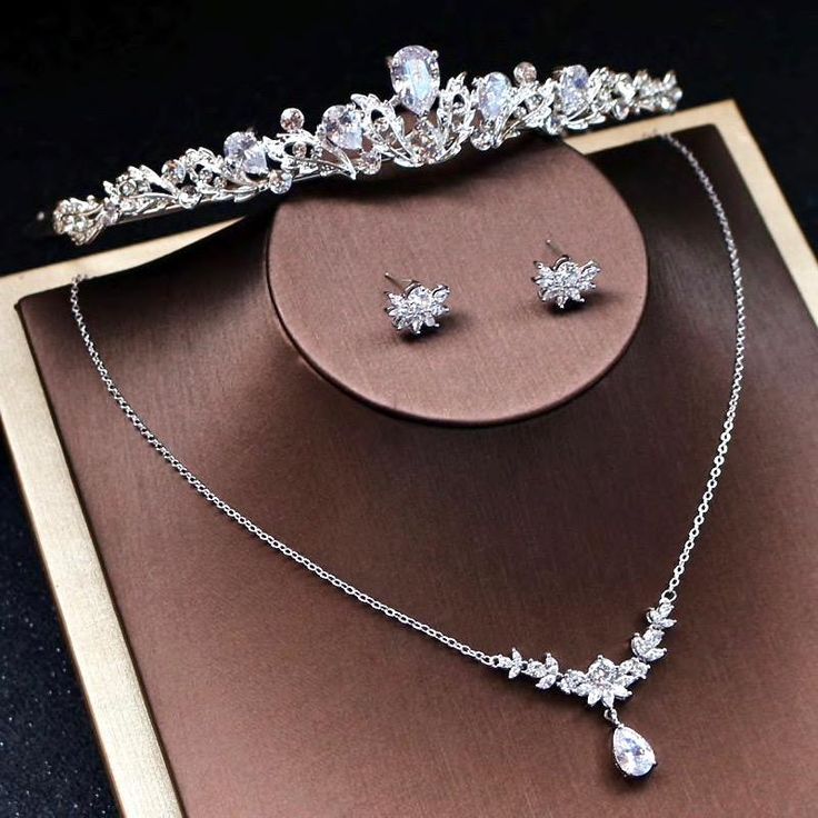 A delicate three-piece bridal jewelry set for the romantic bride! Adorned with intricately faceted cubic zirconia that capture the light from every angle with a perfectly translucent appeal, the pieces are rhodium plated for a flawless finish which enhances the intricate detailing and conveys a modern take on old elega White Cubic Zirconia Bridal Accessories For Wedding, Elegant Crystal Bridal Sets For Bride, Dazzling Diamond-accented Jewelry Sets For Wedding, Dazzling Diamond Accented Jewelry Sets For Wedding, Cubic Zirconia Bridal Set With Sparkling Stones For Wedding, Sparkling Cubic Zirconia Wedding Rings, Wedding Jewelry Sets With Rhinestones And Cubic Zirconia, Elegant Silver Bridal Sets With Rhinestones, Wedding Jewelry Sets With Rhinestones In Cubic Zirconia