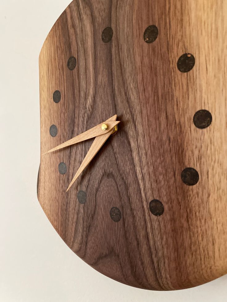 a wooden clock with black dots on it