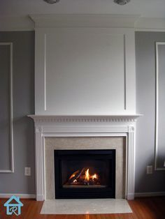 a fire place in the middle of a room with white walls and wood flooring