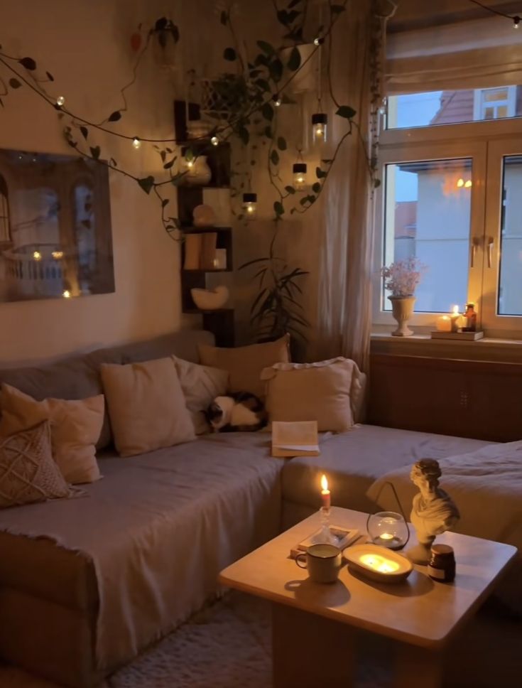 a living room filled with furniture next to a window covered in candles and potted plants