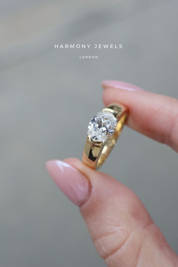 a woman's hand holding a yellow gold ring with a diamond in the middle