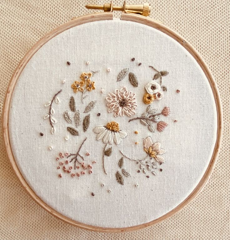 a close up of a embroidery on a piece of cloth with flowers and leaves in it