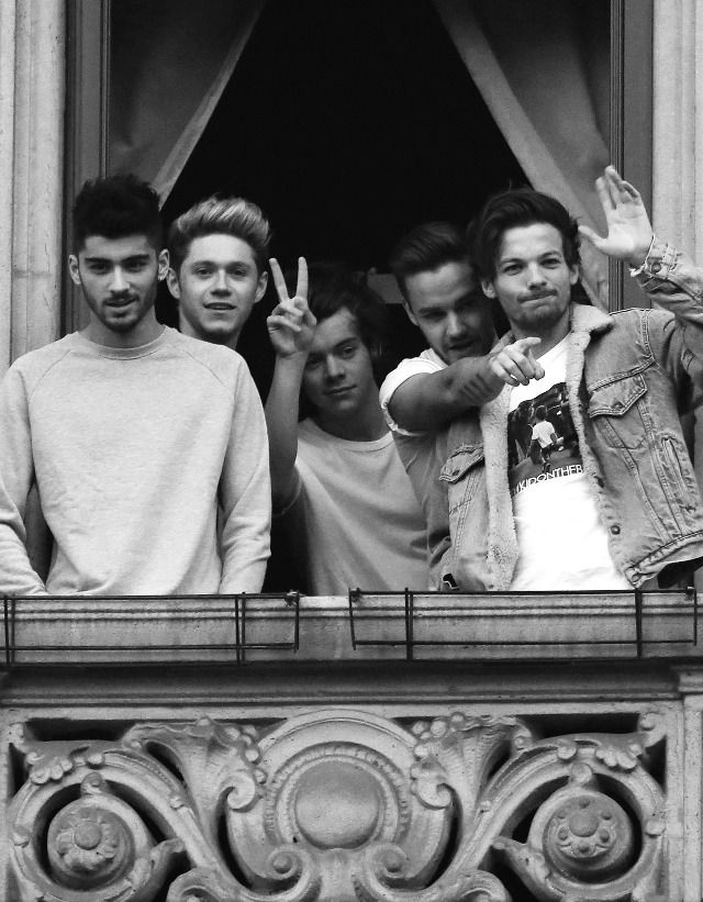 four young men standing in front of a window with one holding up the peace sign