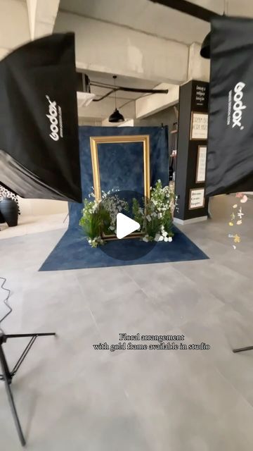 an empty photo studio with blue carpet and white walls, black backdrops and flowers