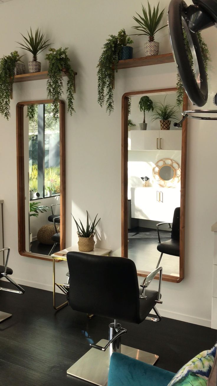 a hair salon with mirrors, chairs and plants on the wall in front of it