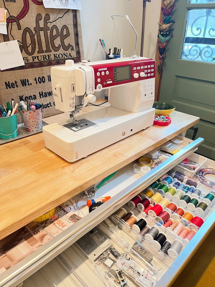 a sewing machine sitting on top of a wooden table next to a drawer filled with craft supplies