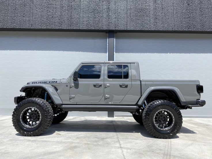 a gray jeep is parked in front of a garage door with black wheels and tires