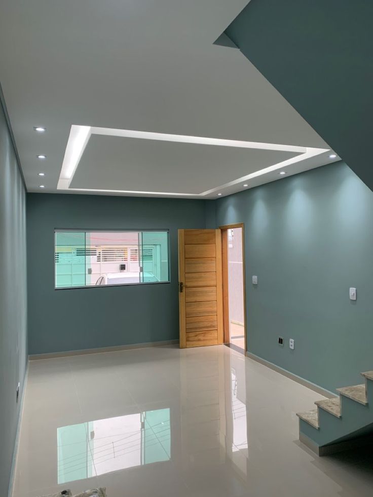 an empty room with stairs leading up to the door and windows on the wall behind it