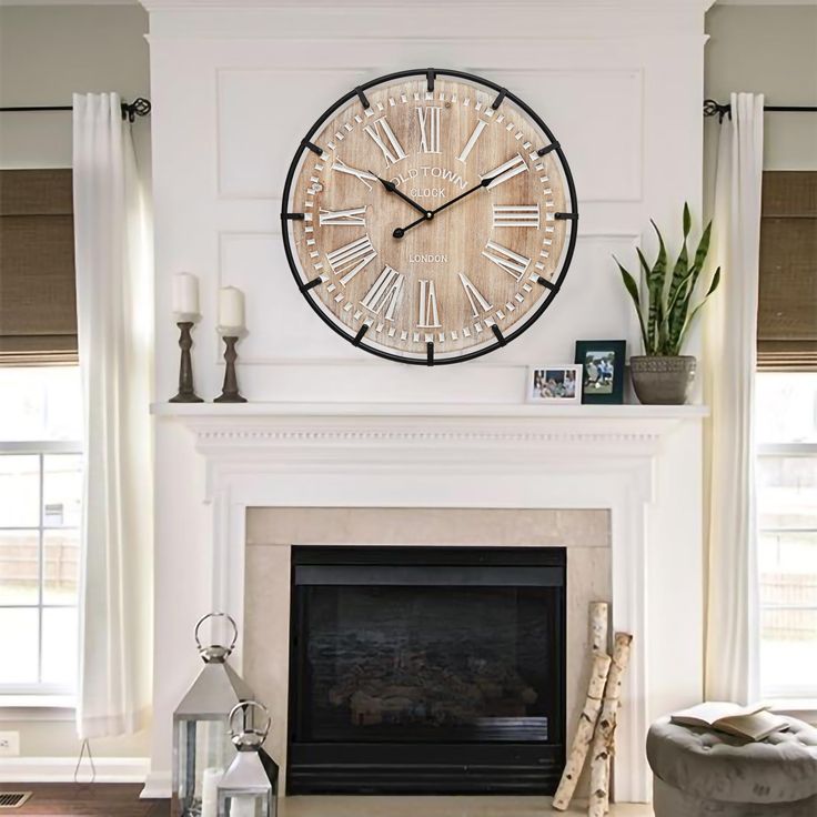 a clock on the wall above a fireplace in a living room with white walls and curtains