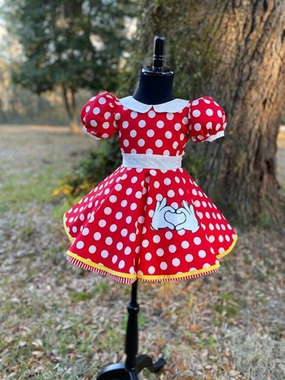 a red and white polka dot dress on a mannequin stand in front of a tree