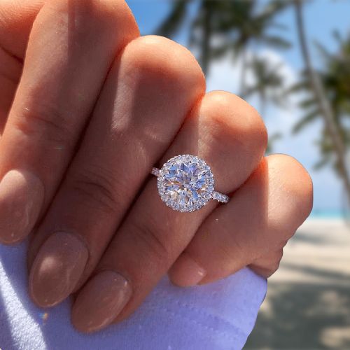 a woman's hand holding an engagement ring with a diamond center in the middle