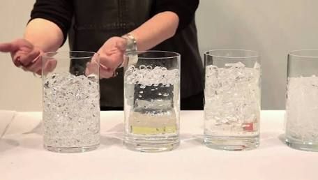 three glasses filled with water and ice on top of a white table next to each other