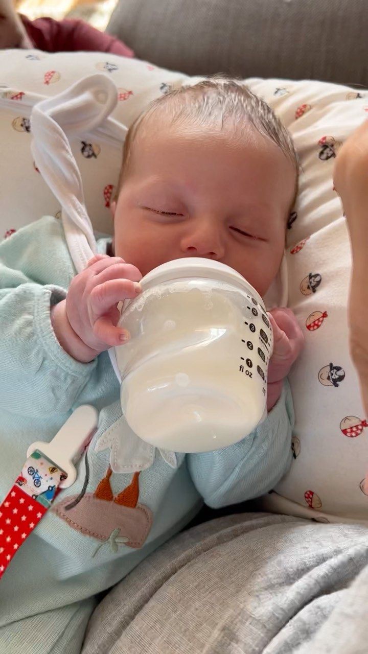 a baby drinking from a cup while laying down