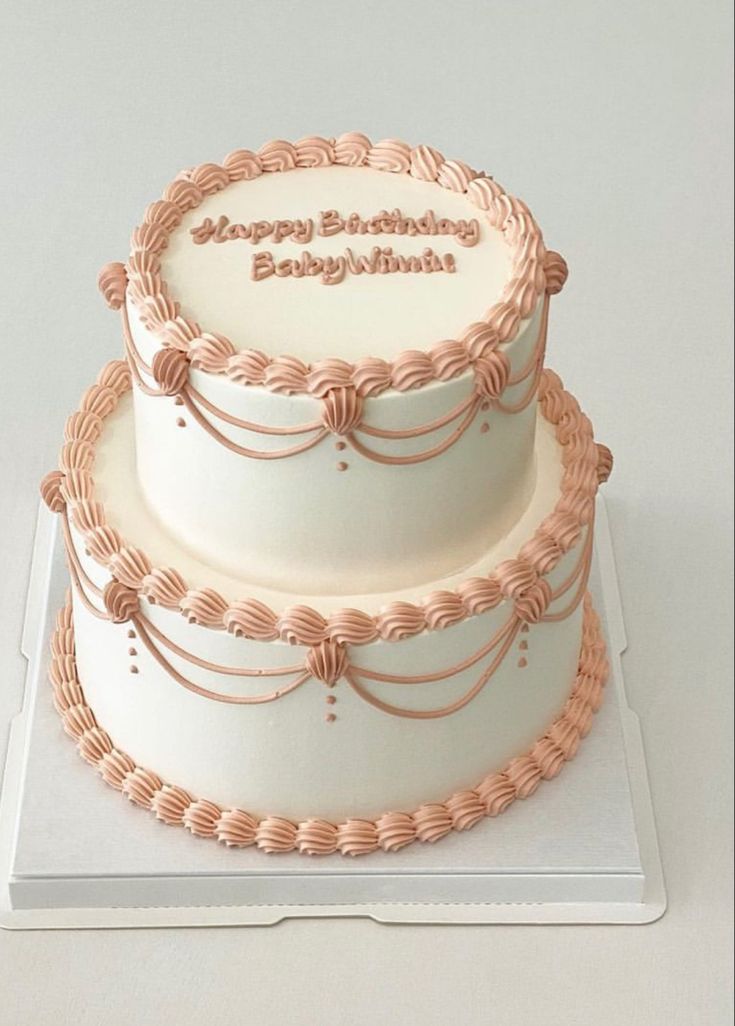 two tiered birthday cake sitting on top of a white plate with pink icing