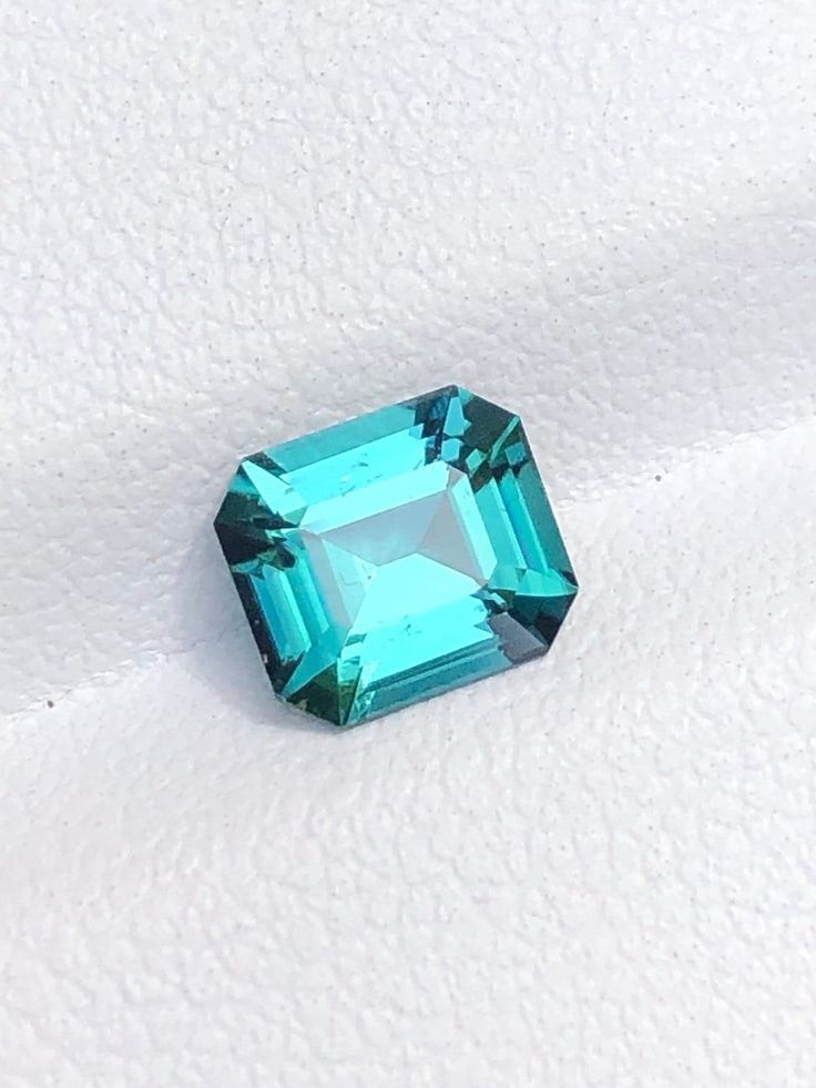 an emerald colored stone sitting on top of a white surface