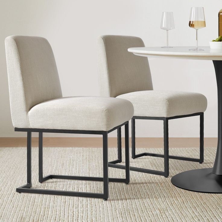 two white chairs sitting next to each other on top of a carpeted floor in front of a table