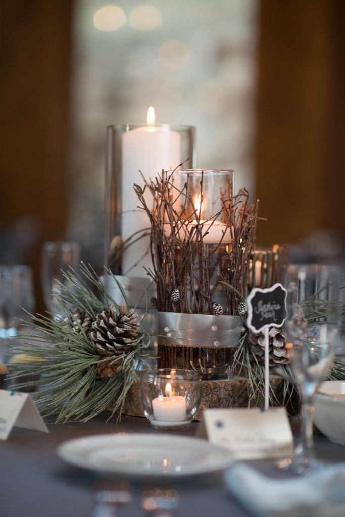 the table is set with pine cones, candles and place settings for an elegant dinner