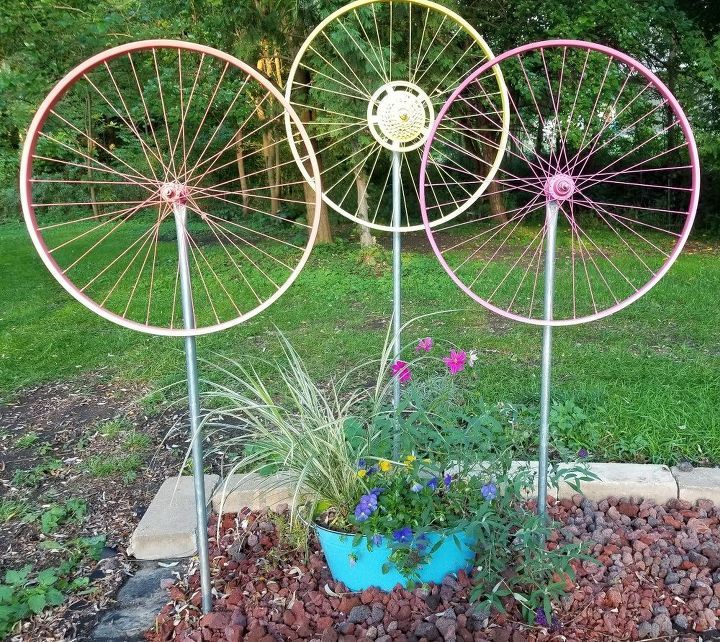 three metal garden art pieces sitting on top of a bed of dirt next to a flower pot