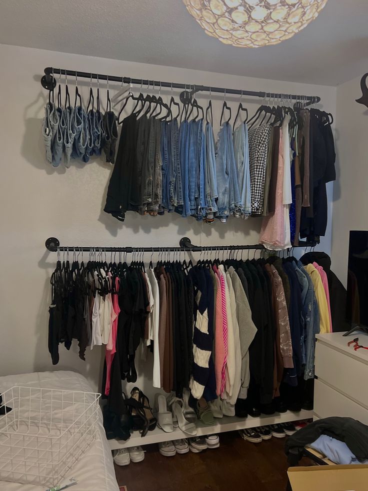 a closet filled with clothes and shoes next to a lamp hanging from the ceiling over a bed