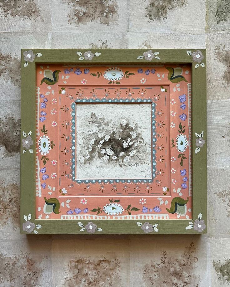 an old photo frame with flowers and leaves on it, hanging on the wall in front of a brick wall